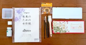 花の絵を描くために必要な本番用の画材一覧図。筆、修正用筆、筆洗い、筆拭き、絵の具、パレット、メラミンスポンジ、マスキング液、ラバークリーナー、水彩紙は必須