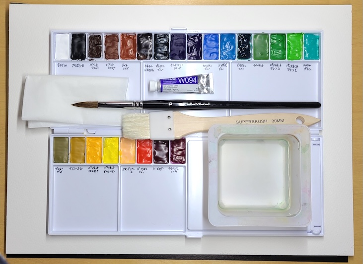 透明水彩の単色見本を描き始める前の机上。ウルトラマリン・ディープと筆、水彩紙が並んでいる様子。