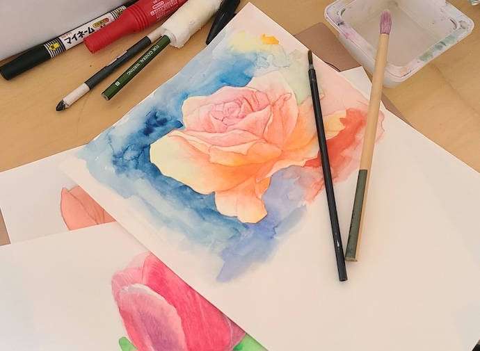 机の上に置かれた描きかけの水彩画と、そっと置かれた筆