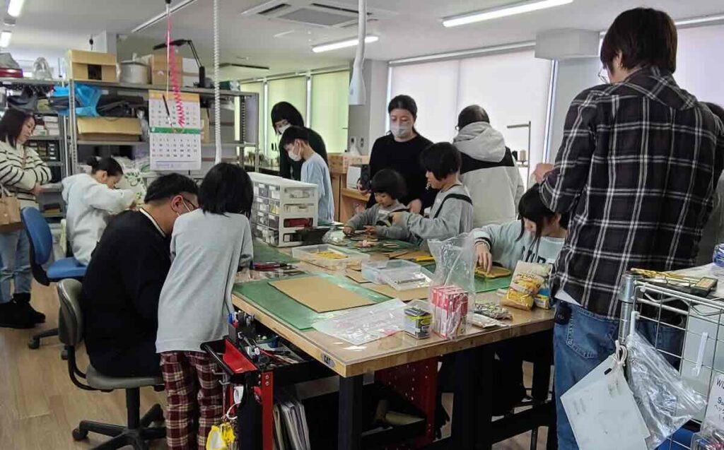 親子や参加者がテーブルを囲んでクリスマスリース作りをしている様子