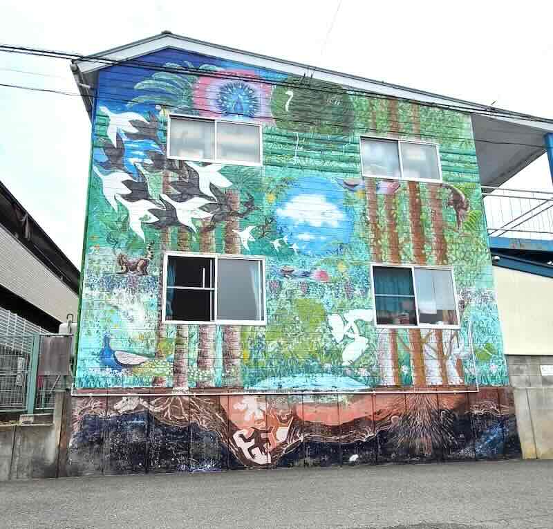 建物の壁一面に森や鳥が描かれた地域壁画の完成作品